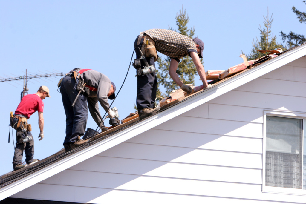 Three men on a roof installing new shingles